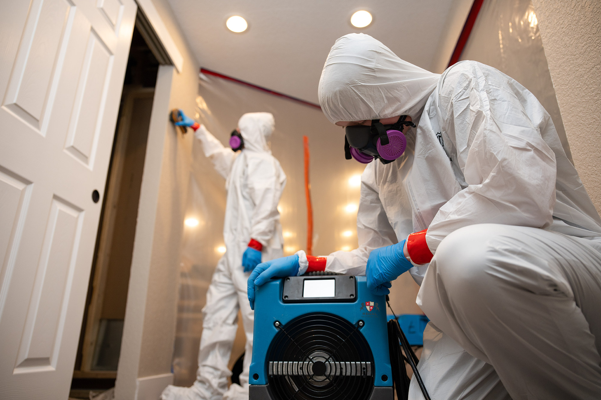 Regal Restoration technicians in protective suits running an air scrubber during mold containment